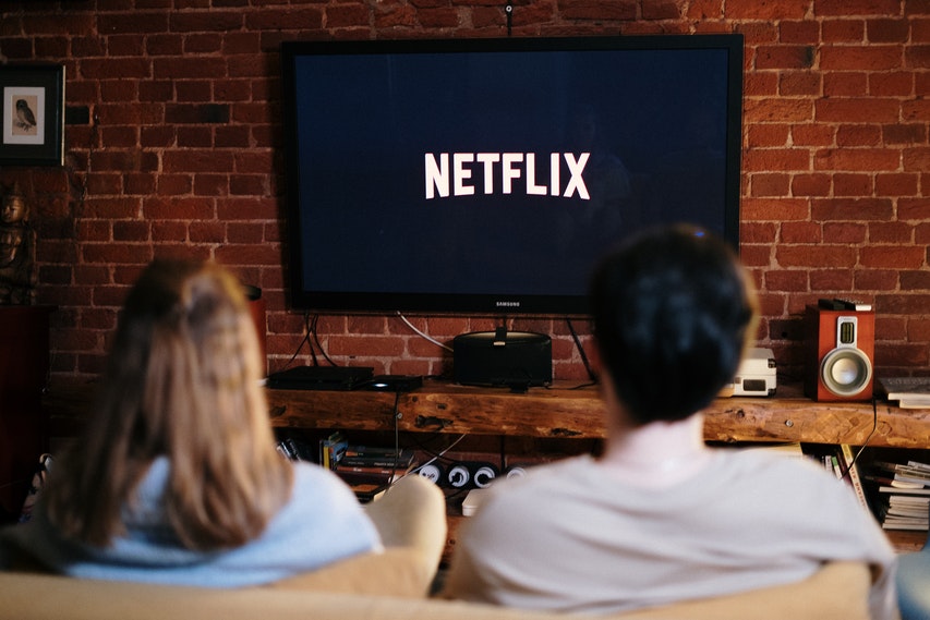 Man and Woman Sat On Sofa Watching Netflix