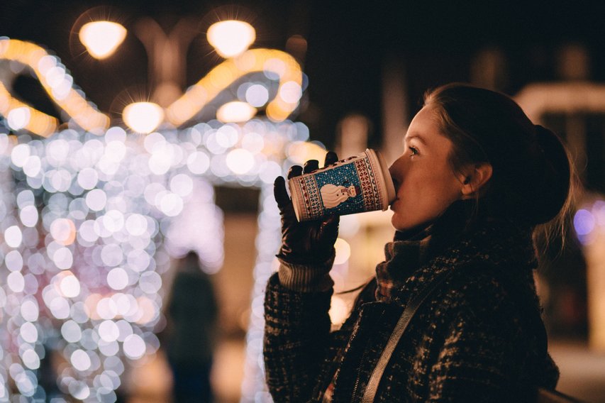 Lady drinking a hot drink outside Strasbourg Christmas market